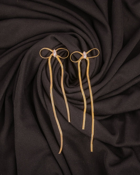 Three gold hairpins on a dark fabric background