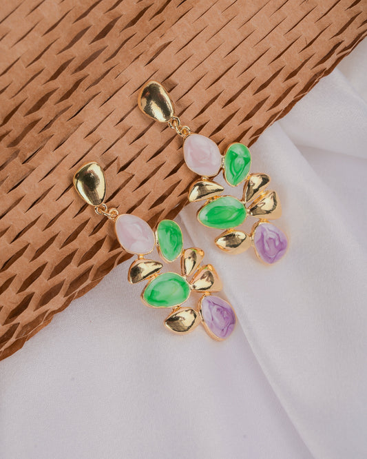 Gold earrings with colorful gemstones on a textured brown and white background
