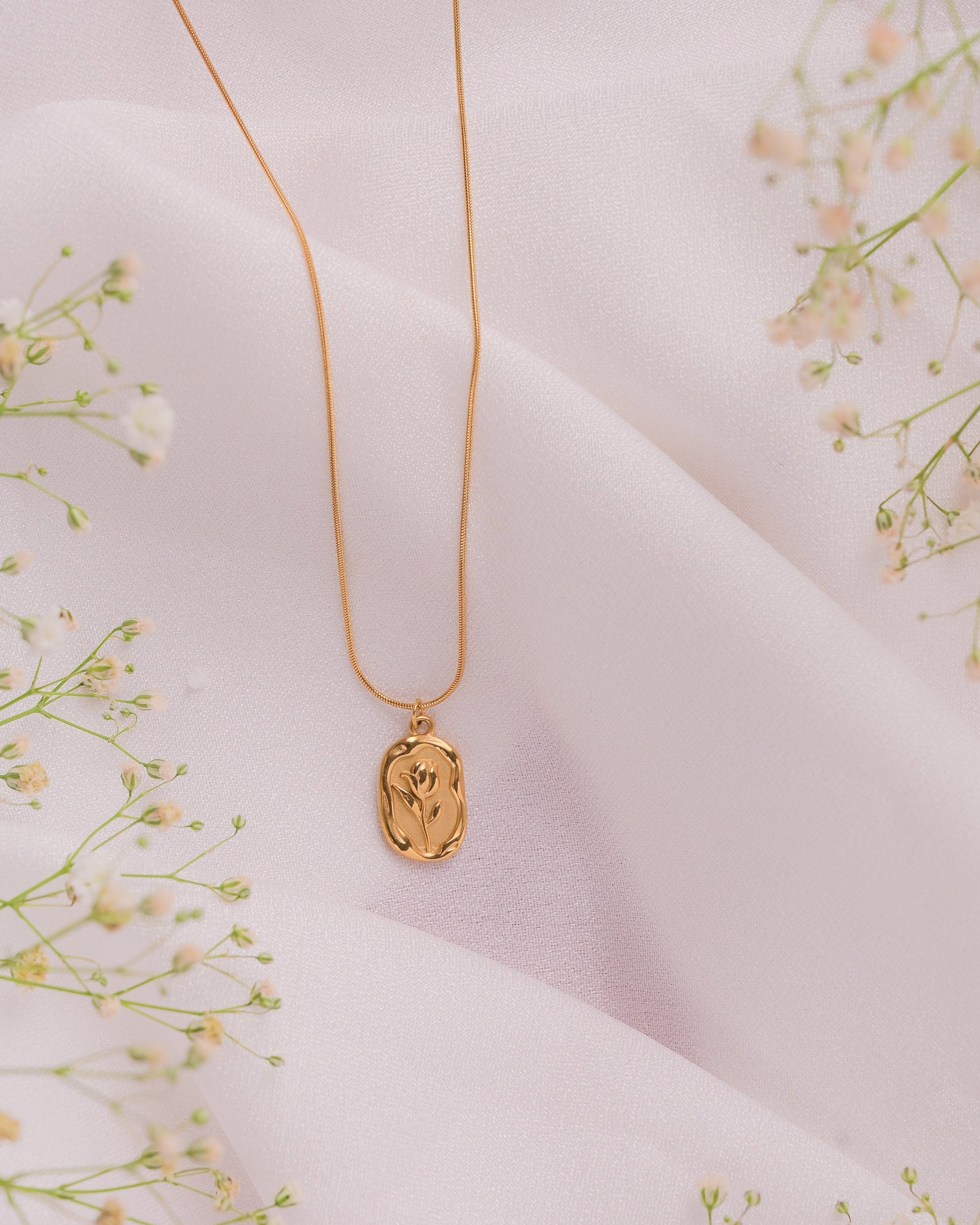 necklace on a light pink fabric background with small white flowers.