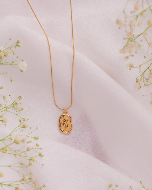 necklace on a light pink fabric background with small white flowers.