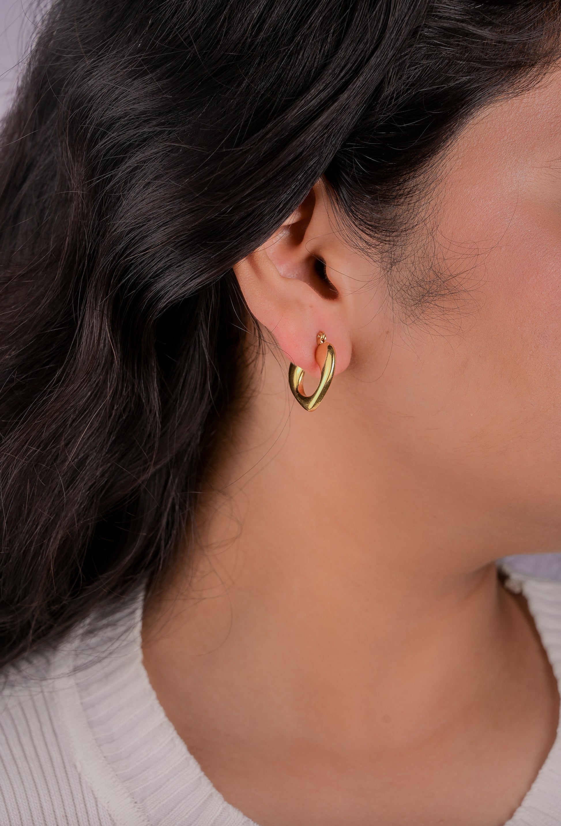 Close-up of a person wearing a gold hoop earring with a blurred background
