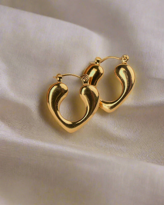 Gold earrings on a textured beige surface