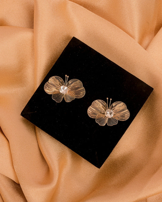 Floral earrings on a black box with a beige fabric background